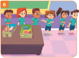 Imagem: Ilustração 6. O grupo e mais dois alunos estão lado a lado próximos da mesa onde estão duas maquetes do interior de uma casa.  Fim da imagem.