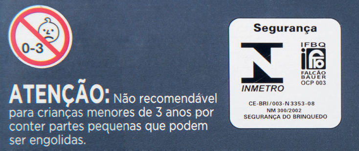 Imagem: Fotografia. Em fundo azul-escuro, à esquerda, uma placa redonda branca com contorno em vermelho e linha na diagonal para à esquerda, indicando 0 – 3 e ilustração em preto e branco de cabeça de criança.  Na parte inferior, texto em branco : atenção : Não recomendável para crianças menores de 3 anos por conter partes pequenas que podem ser engolidas.  À direita, selo de segurança da INMETRO. À direita, IFBQ Falcão BAUER OCP 003 Na parte inferior, texto : CE-BRI/003-N3353-08 NM 300/2002 Segurança do Brinquedo.  Fim da imagem.