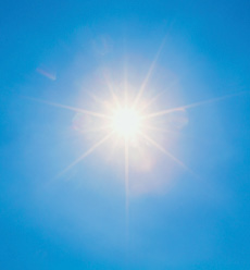 Imagem: Fotografia. Céu de cor azul-claro com sol redondo amarelo, com raios irradiando.  Fim da imagem.