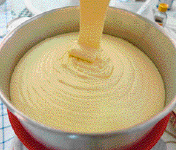 Imagem: Fotografia. De cima para baixo, forma arredondada em cinza, com massa de cor bege-claro na vertical, caindo sobre a forma.  Fim da imagem.