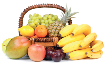 Imagem: Fotografia. Cesto de cor marrom, com cachos de uvas em verde-claro, com frutas em amarelo, verde, abacaxi e folhas verdes. Na parte inferior, manga redonda em verde, maçã em vermelho, frutas arredondadas em marrom-escuro. À direita, cachos de bananas de cor amarela. Fim da imagem.