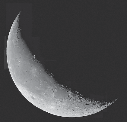 Imagem: Fotografia. Sobre o céu de cor preta, com lua redonda de cor cinza, com parte fina à esquerda, clara e o resto para à direita, com sombra em preto.  Fim da imagem.