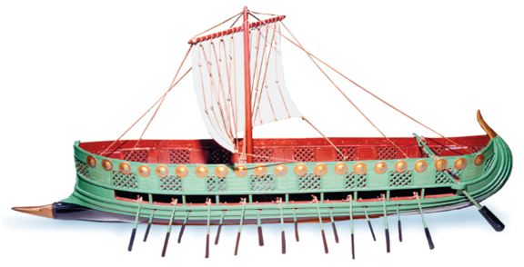 Imagem: Fotografia. Embarcação na horizontal de cor verde, fina, com ponta fina à esquerda, parte inferior com dezenas de aberturas por onde há remos. Na parte superior, de dentro, cor vermelha. Ao centro, mastro, parte reta na vertical com vela de cor branca e hastes finas na diagonal.  Fim da imagem.