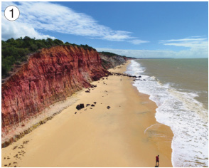 Imagem: Fotografia 1. À direita, orla da praia e à esquerda, montanhas. Fim da imagem.