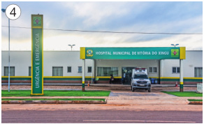 Imagem: Fotografia 4. Uma ambulância parada na frente de uma construção grande. Ao lado, placa com a informação: HOSPITAL MUNICIPAL.  Fim da imagem.
