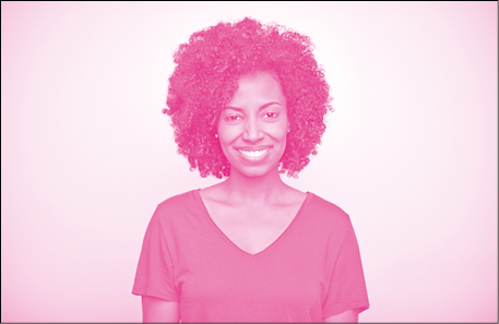 Imagem: Fotografia em tons de rosa. Mulher de cabelo cacheado castanho, vestindo camiseta. Fim da imagem.