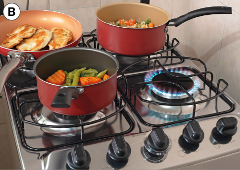 Imagem: Fotografia. B: Fogão a gás com panelas sobre as bocas de chamas acesas. Fim da imagem.