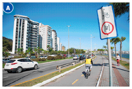 Imagem: Fotografia A. Uma pessoa andando de bicicleta em uma ciclovia. Ao lado, uma placa com o desenho de uma bicicleta. Do outro lado, um carro em uma rua asfaltada. Ao fundo, árvores e prédios.  Fim da imagem.