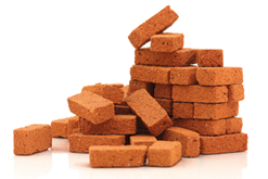 Imagem: Fotografia. Blocos de tijolos empilhados.   Fim da imagem.