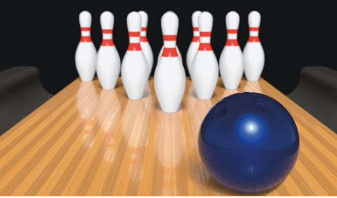 Imagem: Fotografia. Pinos brancos enfileirados sobre um piso. À frente, uma bola preta. Fim da imagem.