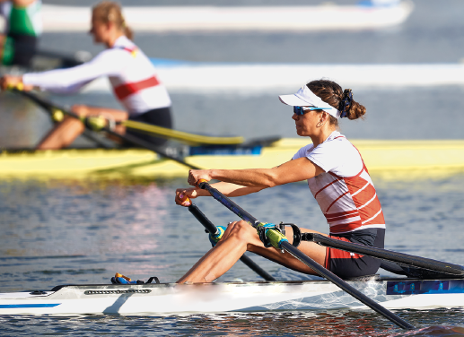 Imagem: Fotografia. Duas mulheres em um barco, segurando remos com as mãos. Fim da imagem.