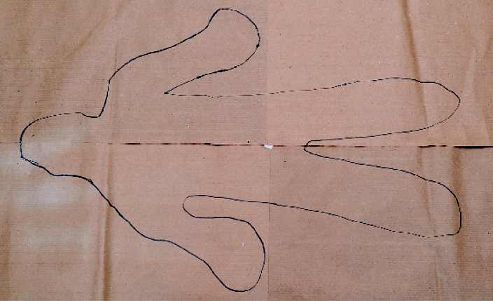 Imagem: Fotografia. Folhas de papel pardo com o desenho do contorno do corpo de uma pessoa.   Fim da imagem.