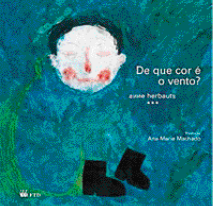 Imagem: Ilustração. Capa de livro. Desenho de um menino de roupa azul, botas pretas e bochechas pintadas de vermelho. Ele está com os olhos fechados. Ao lado, título do livro: de que cor é o vento?  Fim da imagem.