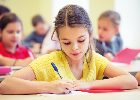 Fotografia 1. Destaque de uma menina que escreve sentada à carteira na sala de aula. 