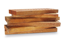 Imagem: Fotografia. Pedaços retangulares de madeira empilhados. Fim da imagem.