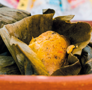 Imagem: Fotografia. Um bolinho amarelo dentro de uma folha. Fim da imagem.