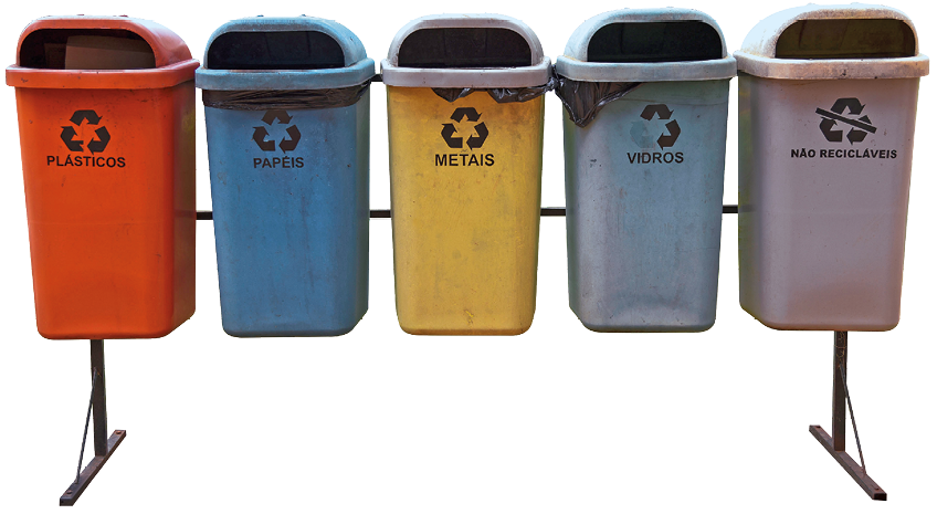 Imagem: Fotografia. Um suporte composto por cinco lixeiras lado a lado. Cada um tem uma cor e é destinado para um tipo de material e todos apresentam o sinal da reciclagem, formado por um triângulo feito de três setas voltadas para o mesmo lado. O primeiro recipiente é vermelho, para plásticos. O segundo é azul, para papéis. O terceiro é amarelo, para metais. O quarto é verde desbotado, para vidros. O quinto é cinza, para não recicláveis e que apresenta um risco de proibitivo sobre o símbolo da reciclagem.  Fim da imagem.