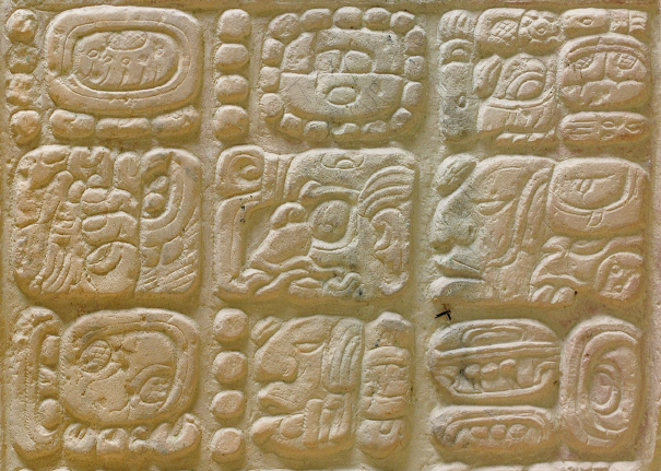 Imagem: Fotografia. Destaque de uma superfície branca com um conjunto de seis desenhos em formato quadrado em relevo.  Fim da imagem.