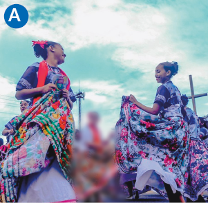 Imagem: A. Fotografia. Destaque de duas mulheres negras que usam longos vestidos rodados e estampados e dançam se olhando frente a frente.  Fim da imagem.