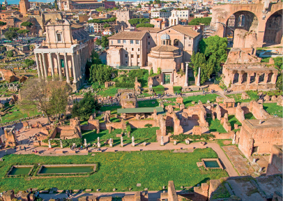 Imagem: Fotografia. Vista aérea de uma extensa construção com áreas em ruínas e jardim preservado. As paredes do local apresentam colunas e arcos.  Fim da imagem.