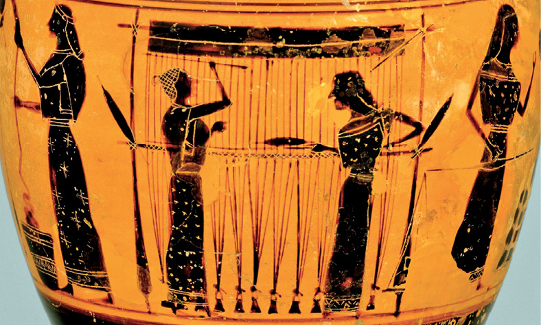 Imagem: Fotografia. Destaque de um vaso que apresenta superfície amarela com pinturas em preto. Há quatro mulheres de pé que desempenham diferentes atividades, duas estão ao centro diante de uma cortina e outras duas estão nas pontas da figura. Elas usam longos vestidos e têm acessórios na cabeça.  Fim da imagem.