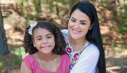Imagem: Fotografia. Retrato de uma mulher e uma criança que sorriem para foto.  Fim da imagem.